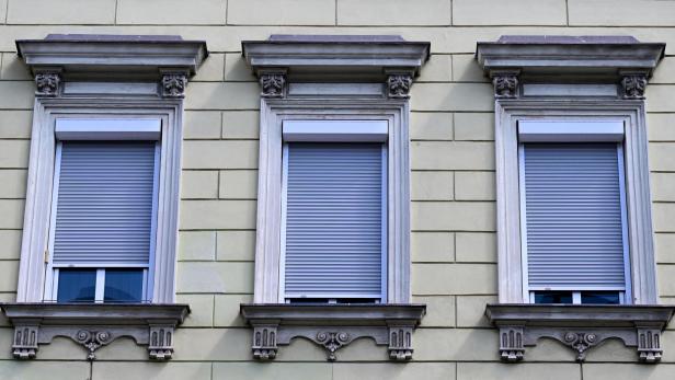 Drei Fenster eines Wohnhauses in einer Reihe mit Rollläden 