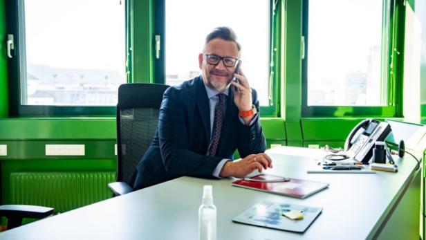 Oliver-John Perry mit Telefon an einem Schreibtisch
