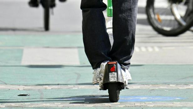 ++ THEMENBILD ++ E-SCOOTER / E-FAHRZEUG / HELMPFLICHT / VERKEHR / VERKEHRSSICHERHEIT Ein junger Mann fährt mit einem Elektroroller auf der Straße.