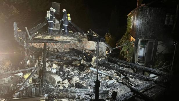 Feuerwehrleute untersuchen  ausgebranntes Dach