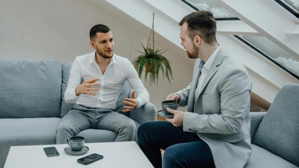 Zwei Männer sitzen auf einer Coach und diskutieren
