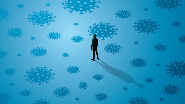 In einer Illustration steht ein Mann allein zwischen Darstellungen von Corona-Viren. Damit soll die schwierige Situation von Patienten mit ME/CFS sowie Long Covid und Post Covid bildlich dargestellt werden.