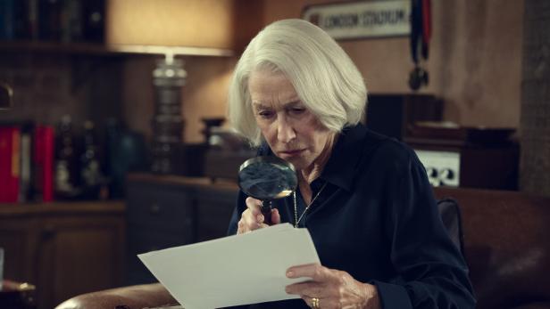 Helen Mirren als Elizabeth im Film "Thursday Murder Club" studiert ein Dokument mit einer Lupe