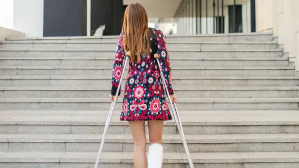 Frau auf Krücken überwindet Treppen