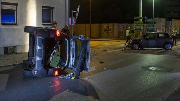 Ein Auto mit geöffnetem Kofferraum liegt nachts seitlich auf einer Straße.