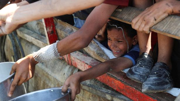 Palestinians wait to receive food from a charity kitchen, amid a hunger crisis, in Gaza City