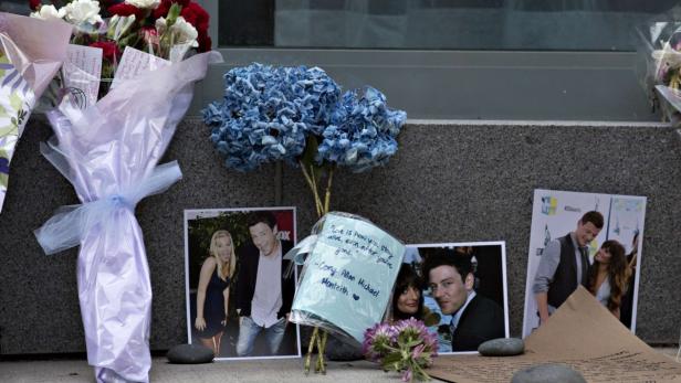 Flowers and photos are left at a small memorial for Canadian actor Cory Monteith outside a downtown hotel in Vancouver, British Columbia July 15, 2013. Monteith, the 31-year-old heart throb of the musical comedy television series &quot;Glee&quot;, was found dead in his hotel room on Saturday. REUTERS/Andy Clark (CANADA - Tags: ENTERTAINMENT OBITUARY)