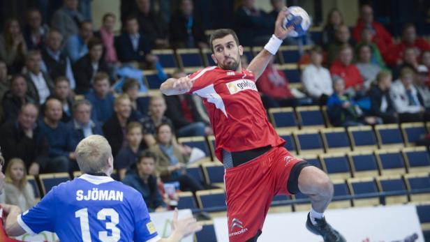 Ein Handballspieler in roter Sportkleidung springt, um einen Ball zu werfen.