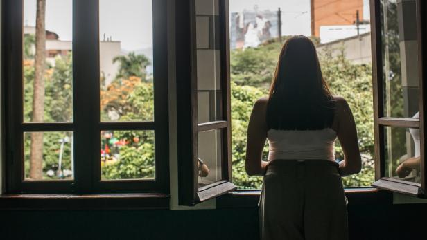 Junge Frau schaut aus dem Fenster.