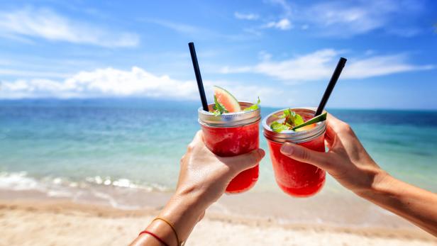 Fresh watermelon juice in two glasses against a bright tropical landscape, background of the sea.