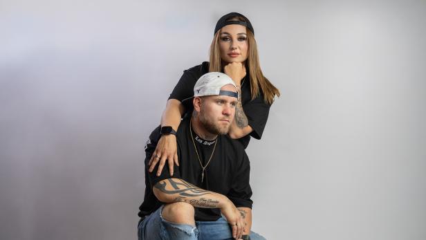 Ein Mann und eine Frau posieren mit Kappen vor der Kamera.
