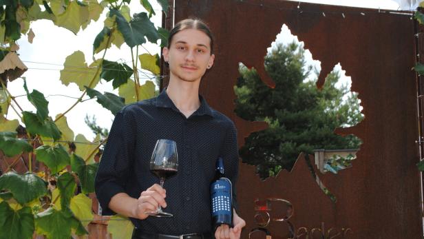 Patrick Bader mit Weinglas und Weinflasche in der Hand
