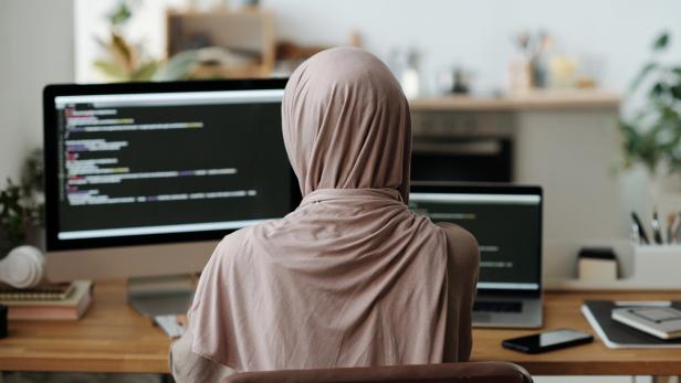 Muslima mit Kopftuch sitzt vor einem Computer.