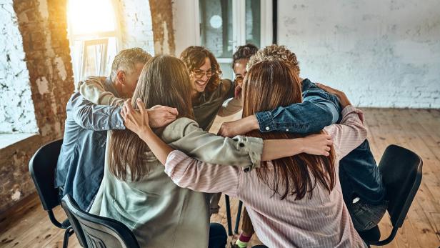 Young people sitting and hugging each other in corporate team building meetings or in group therapy sessions.