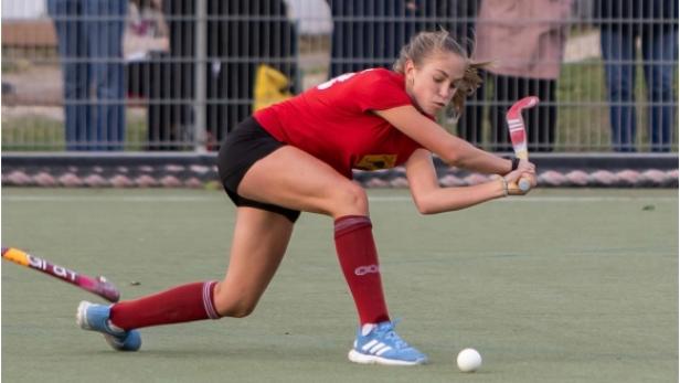 Eine Landhockeyspielerin in einem roten Trikot holt zum Schlag aus