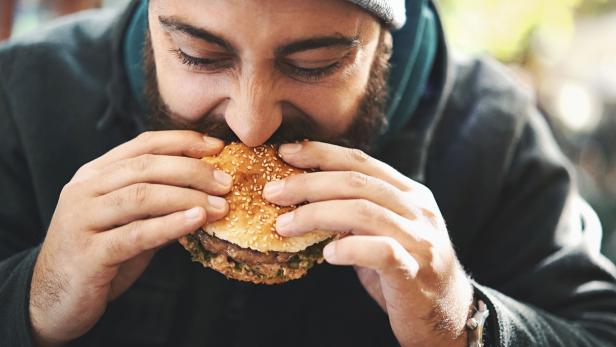Mann beißt in Burger.