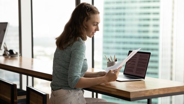 Serious student girl working on research paper, reviewing paper letter