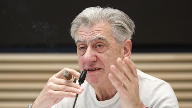 Swatch-Chef Nick Hayek mit Zigarre und zwei Armbanduhren bei einer Bilanzkonferenz.
