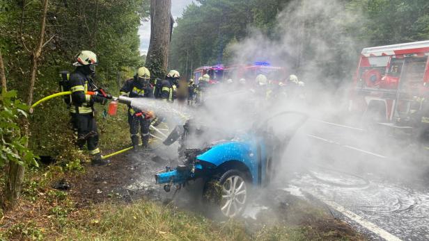 Feuerwehr-Einsatzkräfte löschen das brennende Unfallwrack