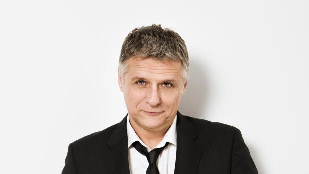 Rainer Nikowitz in einem dunklen Anzug mit Krawatte.