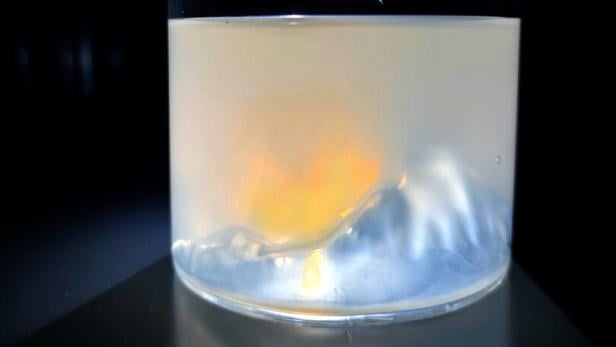 Milchiges Wasser im Glas wir angeleuchtet, es entsteht ein orange-rotes Farbspiel.