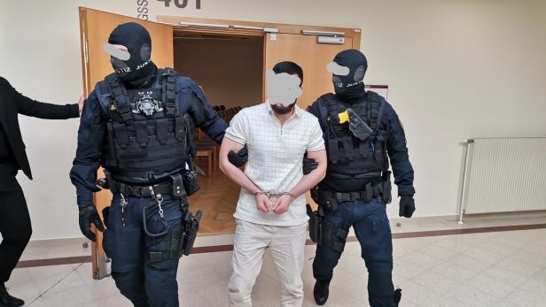 Angeklagter mit zwei Justizwachebeamten vor dem Gerichtssaal.