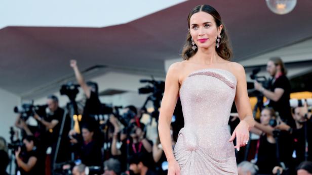 Emily Blunt in einem weiß schimmernden schulterfreien Kleid auf dem roten Teppich der Filmfestspiele in Venedig.