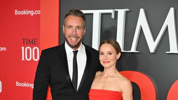 Dax Shepard im schwarzen Anzug und Kristen Bell im roten, schulterfreien Outfit posieren gemeinsam auf einem roten Teppich.