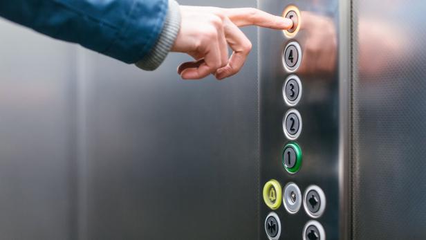 Finger drückt auf Liftknopf