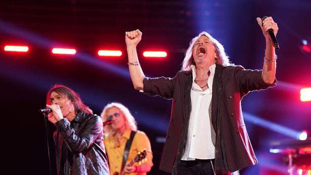 Luis Maldonado und Kelly Hansen von Foreigner stehen auf einer Bühne und singen leidenschaftlich unter bunten Lichtern.