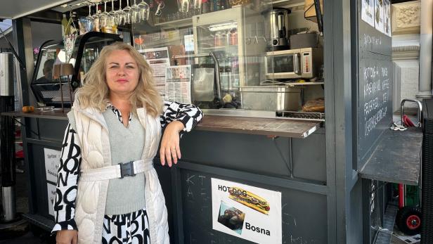 Eine Frau steht vor einem Würstelstand