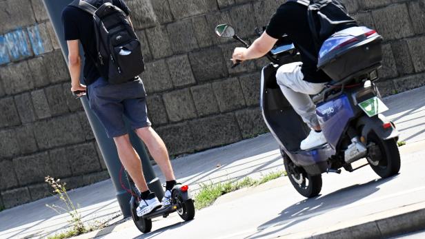 Zwei Personen fahren mit E-Scooter und E-Moped auf der Straße.