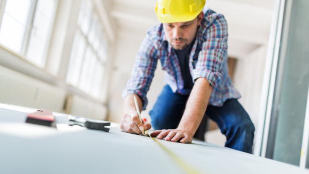 Construction Worker With Tape Measure On Site