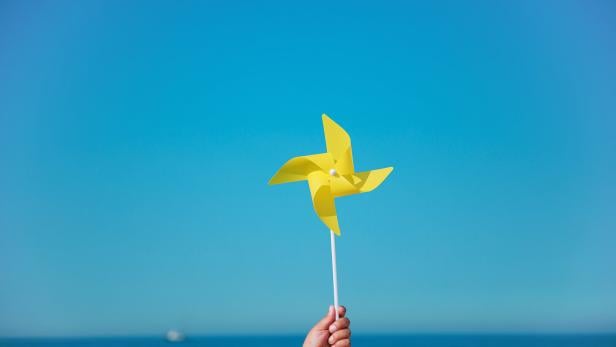 Hand holding yellow pinwheel in the sea Hand holding yellow pinwheel in the sea