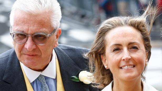Prinz Laurent und Prinzessin Claire von Belgien Prinz Laurent mit Brille und im Anzug und seine Frau Claire mit blonden Haaren lächeln.