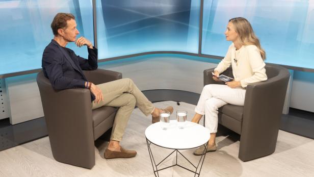 Wolfgang Fojtl Wolfgang Fojtl sitzt im TV-Studio auf einem braunen Couch-Sessel gegenüber von Moderatorin und Journalistin Jennifer Corazza