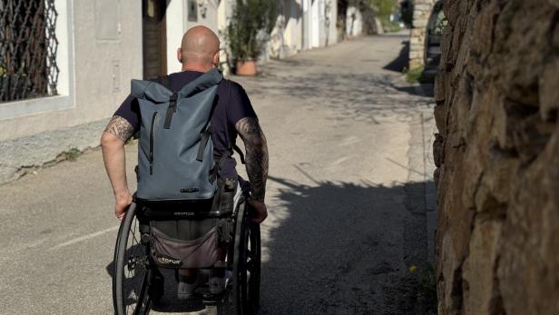 Gerhard ist von hinten im Rollstuhl sitzend zu sehen und fährt eine Kellergasse in der Wachau entlang.