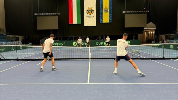 Zwei Tennisspieler während eines Matches auf einem blauen Hallenplatz.