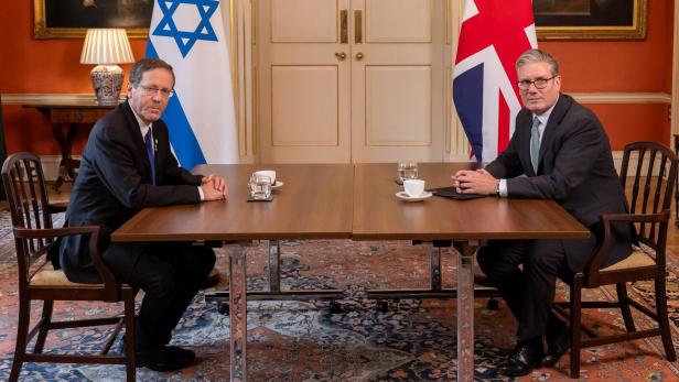 President of Israel Isaac Herzog visits London Herzog und Starmer sitzen an einem Tisch vor den Flaggen Israels und Großbritanniens.