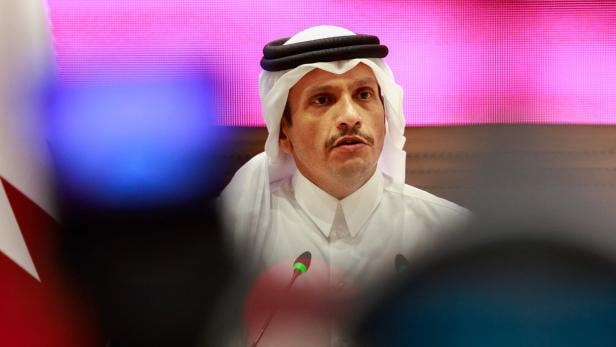 QATAR-ISRAEL-CONFLICT Ein Mann in traditioneller arabischer Kleidung spricht vor Mikrofonen, im Hintergrund leuchtet eine pinke Wand.