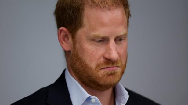 Prinz Harry Prinz Harry mit Vollbart und Hemd blickt nach unten.