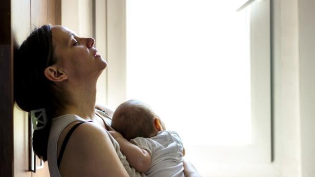 Eine müde, besorgte Mutter wiegt ein schlafendes Baby.
