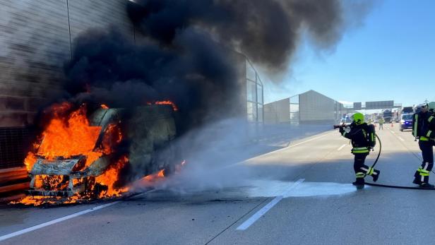 Ein brennendes Fahrzeug wird von Feuerwehrleuten gelöscht