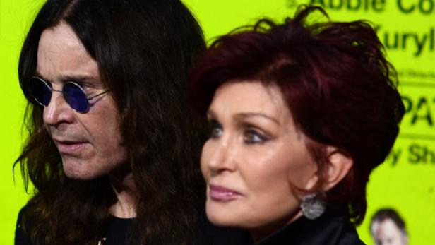 Ozzy und Sharon Osbourne posieren vor einem hellgrünen Hintergrund.