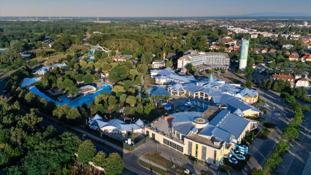 Luftaufnahme eines Resorts mit einem Wasserpark, umgeben von üppigem Grün und blauen Wasserflächen.