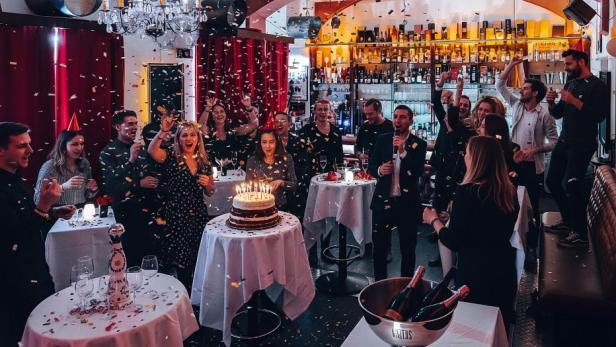 Eine Gruppe von Menschen feiert in einem Restaurant einen Geburtstag mit Kuchen und fröhlicher Stimmung.