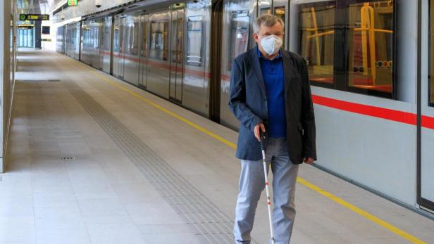 Blinder mit Stock neben U-Bahn.