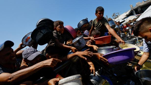 FILE PHOTO: Palestinians wait to receive food from a charity kitchen, in Gaza City
