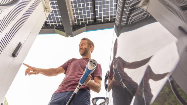 Man Initiating Electric Vehicle Charging Under Solar Canopy