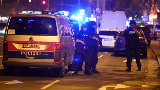 Polizisten mit Gewehren stehen auf der Straße neben einem Polizeiwagen. Polizisten mit Gewehren stehen auf der Straße neben einem Polizeiwagen.